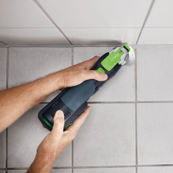 Eine Person verwendet ein Multifunktionswerkzeug zum Entfernen von Fugen zwischen Fliesen.