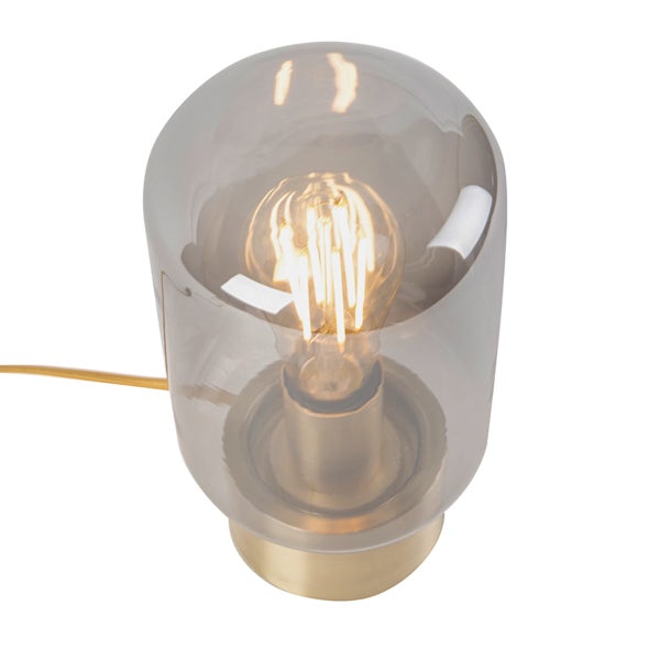 Tischleuchte mit rauchgrauem Glasschirm und rundem Messingfuß inklusive LED-Leuchtmittel im Filament-Stil.