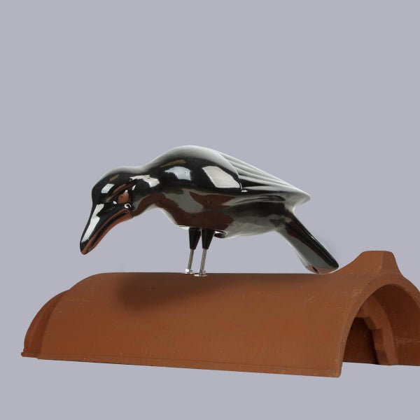Firstfigur aus schwarzer, glasierter Keramik in Form eines Raben, montiert auf einem naturroten Firstziegel.