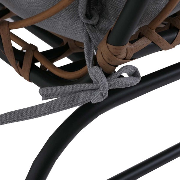 Detailaufnahme eines Gartenstuhls mit grauem Kissen, das mit einem Bindeband an einem Gestell aus schwarzem Metall und braunem Polyrattan befestigt ist.