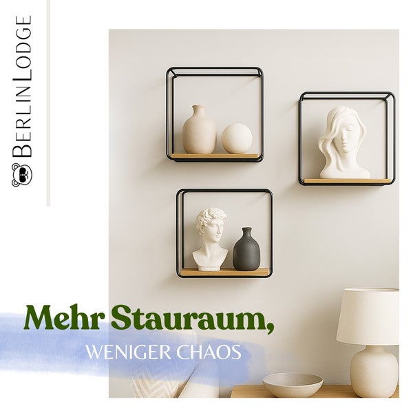Helle, aufgeräumte Szene mit drei quadratischen Wandregalen aus schwarzem Metall und Holz, Vasen, Büsten und einer Lampe. Berlin Lodge Logo.