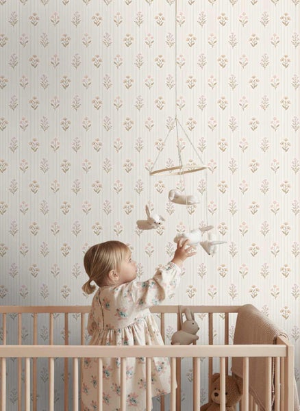 Vliestapete mit feinen Längsstreifen und floralem Muster in einem hellen Kinderzimmer mit Gitterbett aus Holz.