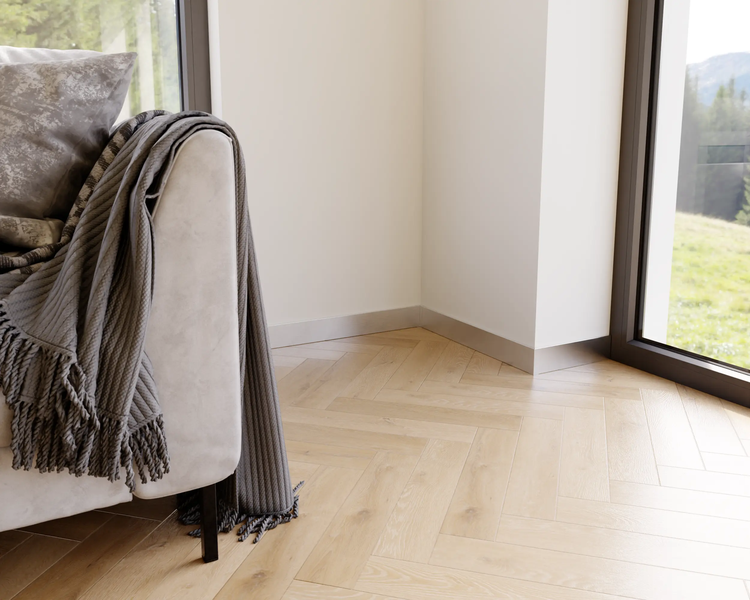 Detailaufnahme eines Wohnzimmers mit Sofa, Kissen, Decke und Parkettboden