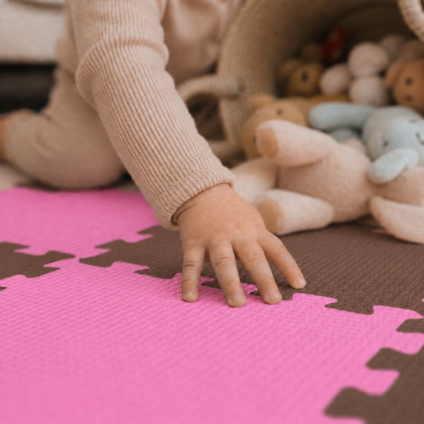 Kind spielt auf einer Puzzlematte mit strukturierter Oberfläche neben einem Korb mit Kuscheltieren.