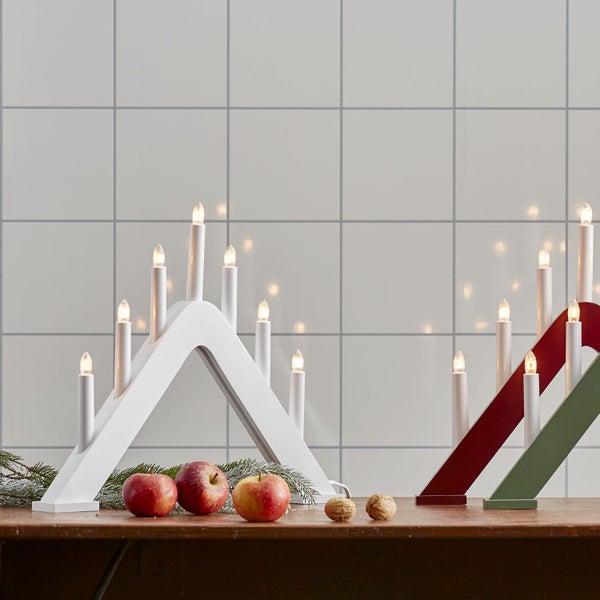 Zwei hölzerne Schwibbögen mit elektrischen Kerzen, Äpfeln und Nüssen auf einem Tisch