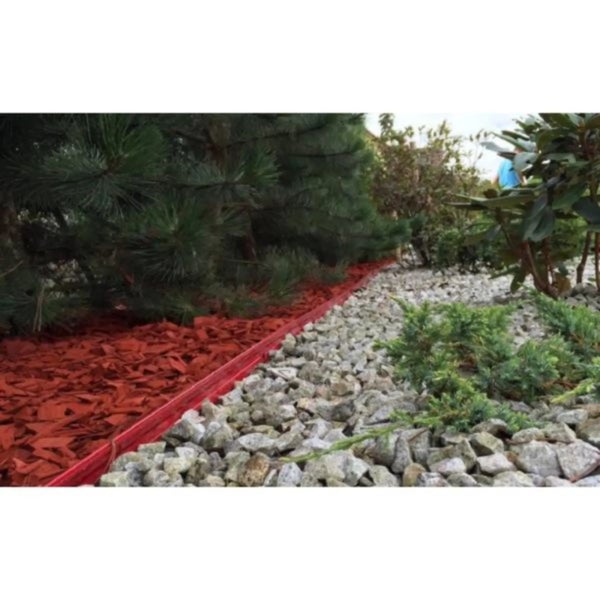 Garten-Beeteinfassung trennt einen Bereich mit rotem Mulch unter Nadelbäumen von einer Fläche mit hellem Zierkies und kleinen Sträuchern.