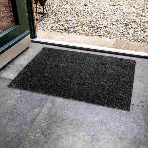 Schmutzfangmatte aus Textil vor einer geöffneten Tür auf Fliesen