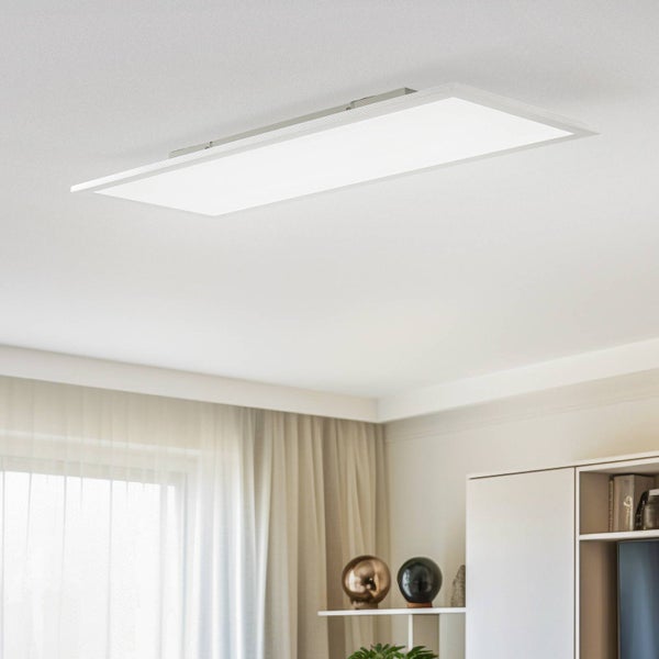 Flaches, rechteckiges LED-Panel an der Decke in einem hellen, modern eingerichteten Wohnzimmer mit hellen Vorhängen und Regalen.