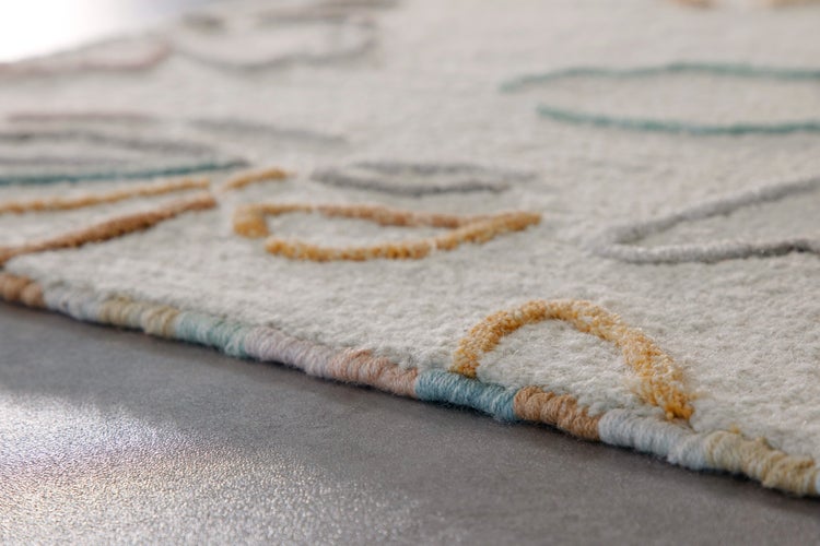 Nahaufnahme eines strukturierten Teppichs mit farbigen abstrakten Mustern und farbigem Rand.
