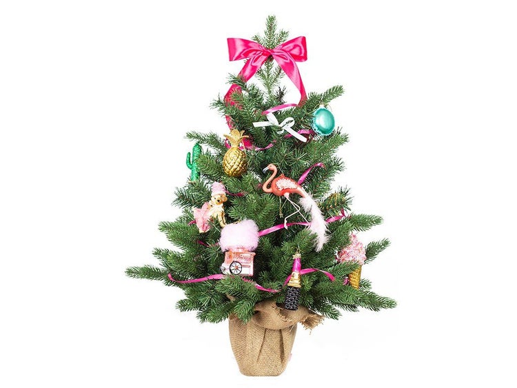 Ein kleiner Weihnachtsbaum im Jutesack, geschmückt mit ausgefallenen Figuren wie Flamingo, Ananas und Eiswaffel sowie einer Schleife.