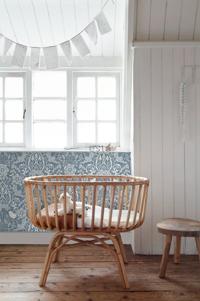 Helles Babyzimmer mit Kinderbett aus Holz, floraler Tapete und Fenster