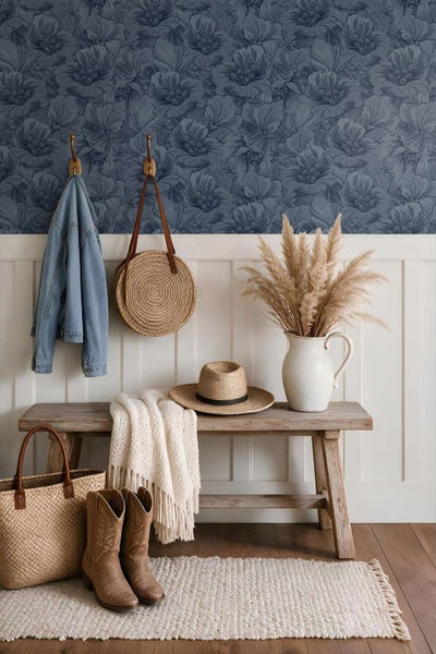 Flur mit Holzbank, Wandpaneelen und florale Tapete. Dekoriert mit Strohtasche, Hut, Strickdecke und einer Vase mit Trockenblumen.