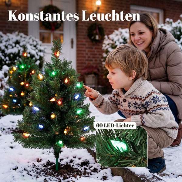 Zwei kleine künstliche Weihnachtsbäume in Tontöpfen dekoriert mit Weihnachtskugeln Schleifen und Lichterketten auf einem Holztisch stehend