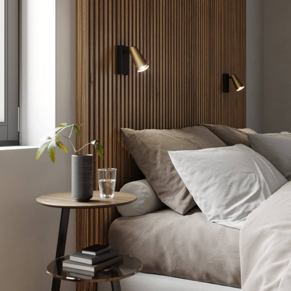 Schlafzimmer mit Holzwand, Nachttisch, Lampe und Bett