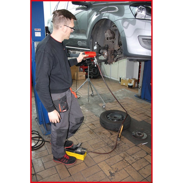 Mechaniker bei der Arbeit mit einem hydraulischen Radnabenabzieher an einem Auto auf einer Hebebühne.