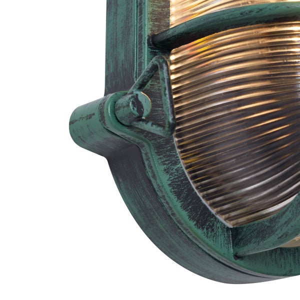 Nahaufnahme einer ovalen Außenwandleuchte aus Metall mit grüner Patina und geriffeltem Glas.