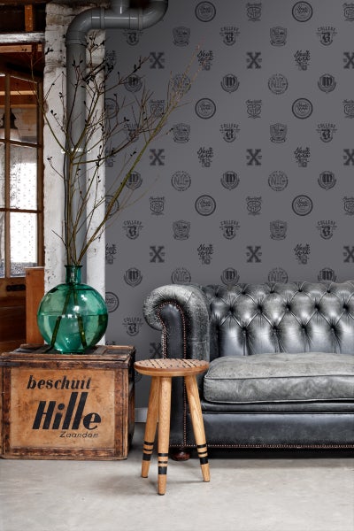 Wohnzimmer mit Sofa, Hocker, Holzkiste und gemusterter Tapete