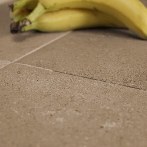 Nahaufnahme einer Bodenfliese in Steinoptik mit sichtbarer Fuge und darauf liegenden Bananen