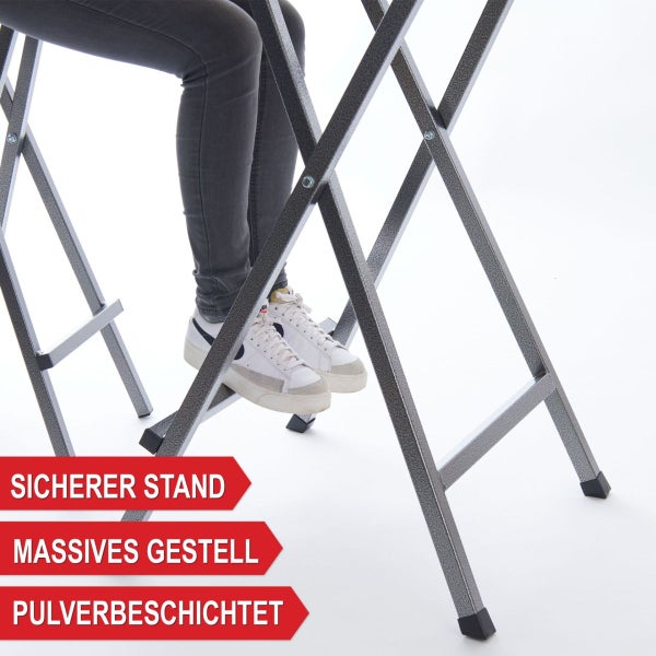 Detailansicht eines massiven, pulverbeschichteten Metallgestells mit sicherem Stand und Füßen einer Person auf der Fußstütze.