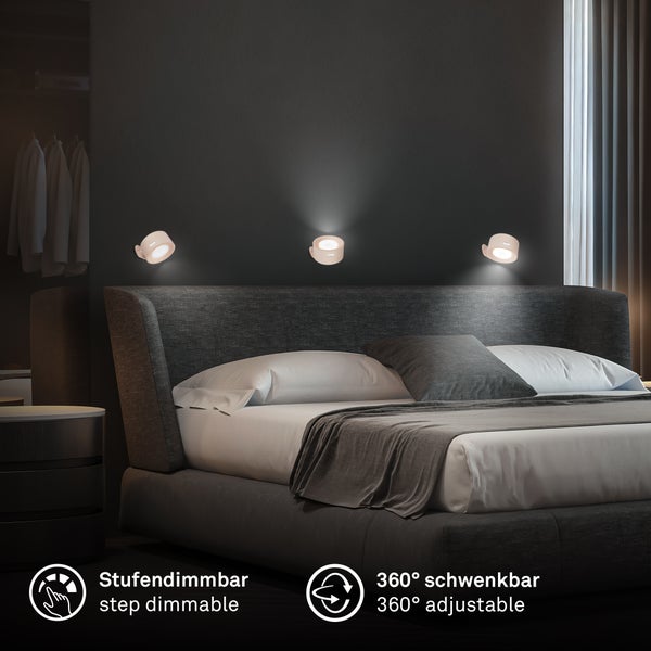 Drei runde LED-Wandspots über einem gepolsterten Bett im modernen Schlafzimmer, 360 Grad schwenkbar und stufendimmbar.
