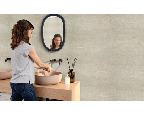 Frau wäscht sich die Hände in einem Badezimmer mit Waschtisch, Spiegel und Fliesen