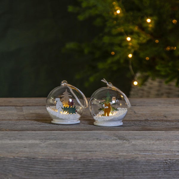 Zwei Weihnachtskugeln mit Wintermotiven auf Holzgrund