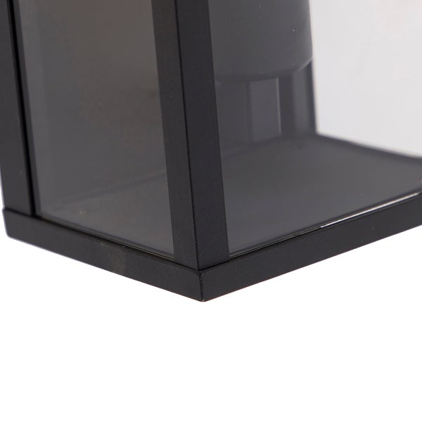 Nahaufnahme einer modernen Außenwandleuchte mit schwarzem Metallrahmen und klaren Glaspaneelen.