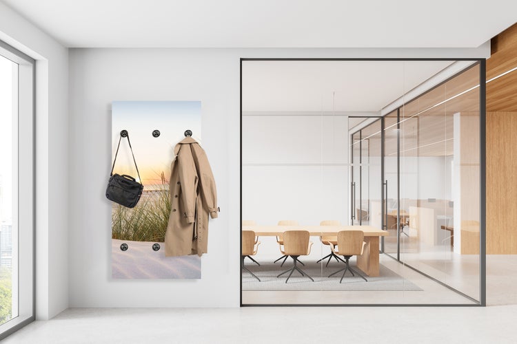 Wandgarderobe mit Strandmotiv, Mantel und Tasche in einem hellen Büro