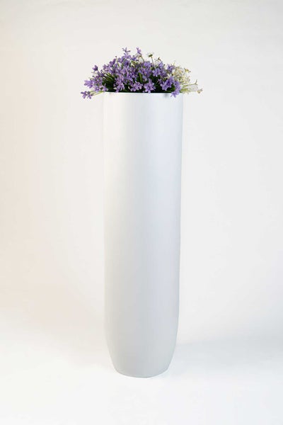Hohe weiße Pflanzsäule mit violetten und weißen Kunstblumen.