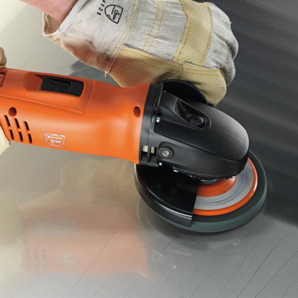Ein orangefarbener Fein Winkelschleifer wird von einer Hand in einem Arbeitshandschuh zum Polieren einer glatten Metalloberfläche verwendet.