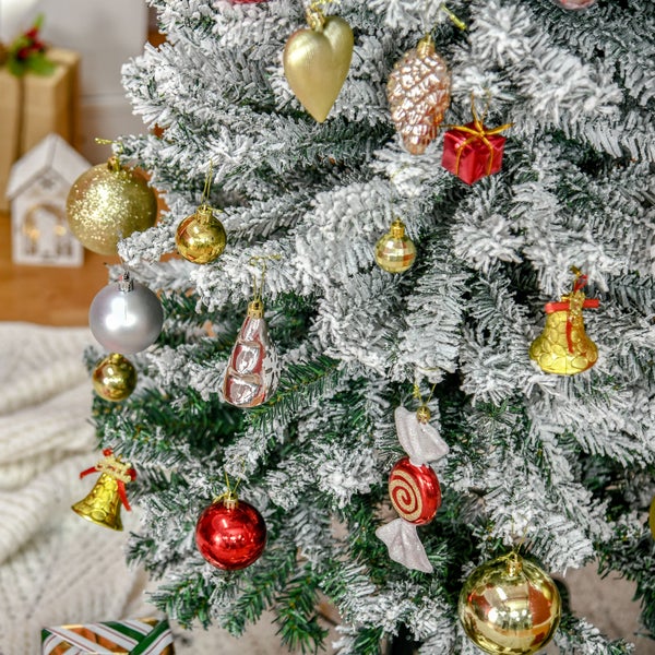 Künstlicher Weihnachtsbaum mit Kunstschnee bedeckt, dekoriert mit verschiedenen Anhängern wie Kugeln, Glocken und Herzen.