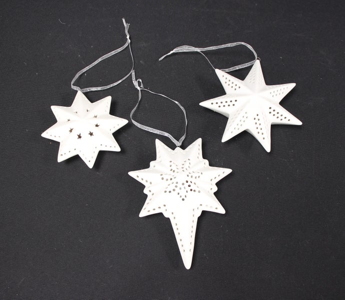 Drei weiße Sterne als Weihnachtsschmuck mit Löchern und Bändern zum Aufhängen.