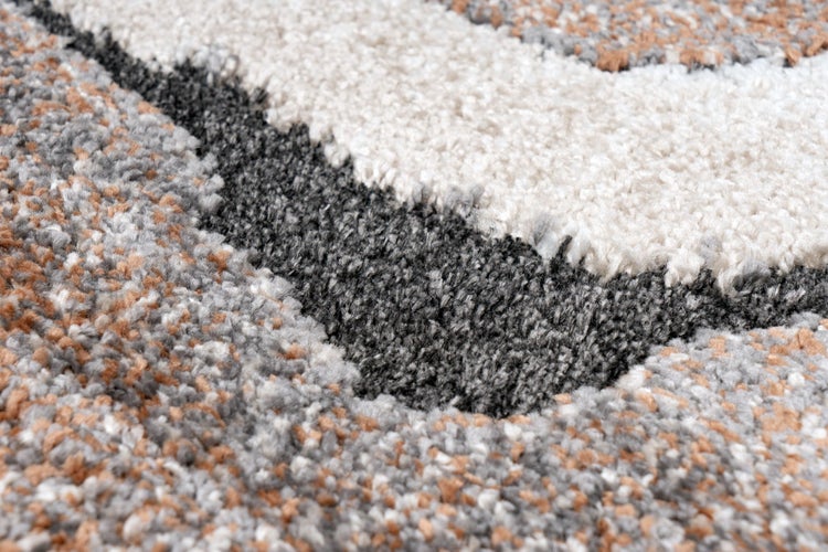 Detailansicht eines Teppichs mit hochflorigem Strukturmuster in wellenförmigem Design.