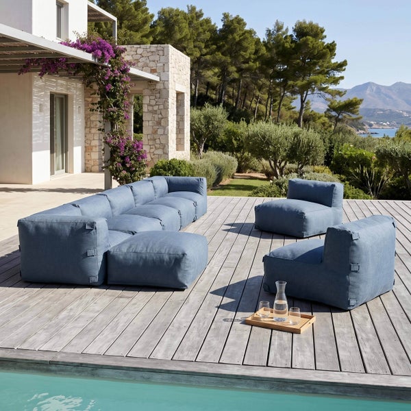 Modulares Gartenlounge-Set auf einer Holzterrasse am Pool mit einem blauen Sofa und zwei Sesseln in einer hellen mediterranen Umgebung.