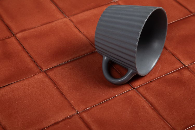 Quadratische Bodenfliesen in Terrakotta mit grauer Tasse