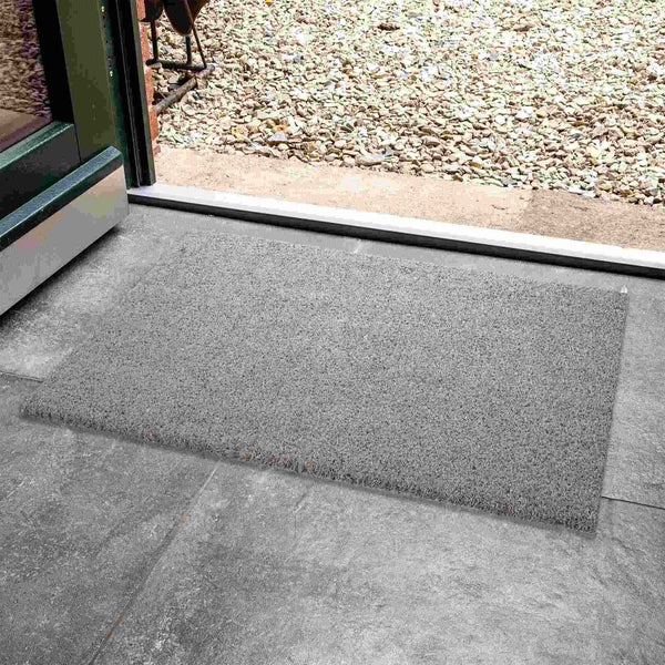 Fußmatte vor einer offenen Tür auf Steinfliesen