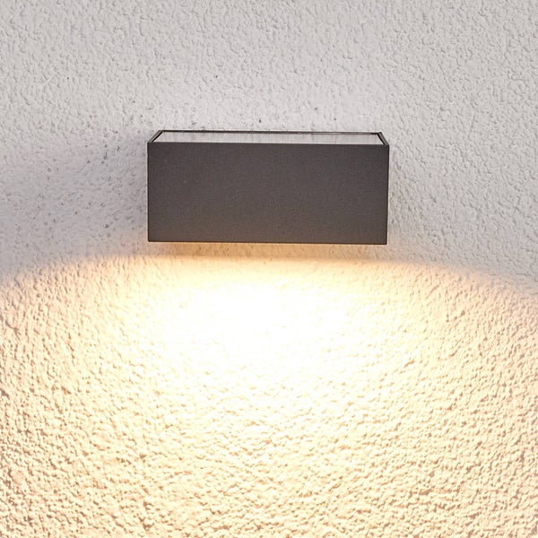 Rechteckige Außenwandleuchte mit Lichtaustritt nach unten auf einer strukturierten Hauswand.