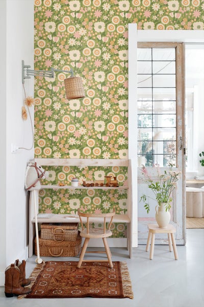 Tapete mit floralem Retro-Muster in Grün, Weiß und Orange in einem hellen Kinderzimmer mit Holzmöbeln.