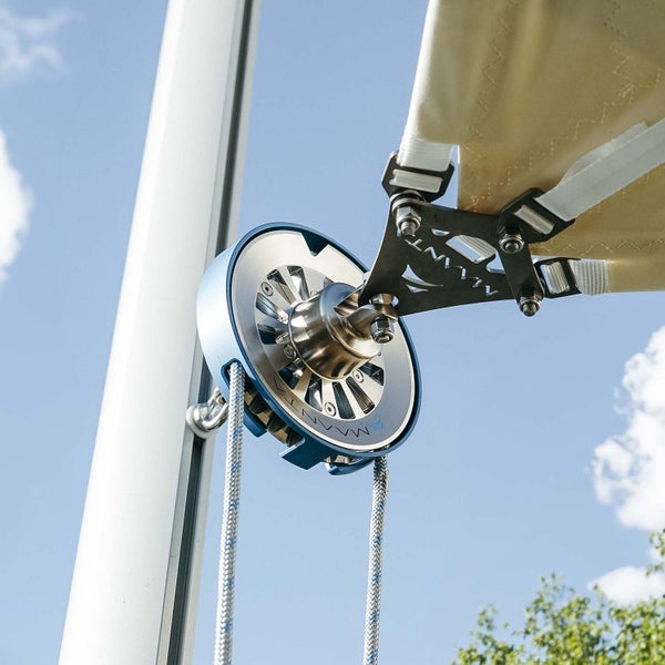 Maanta Rollensystem aus Metall mit blauem Ring zur Befestigung eines hellen Sonnensegels an einem Mast mit Seilführung, Maanta Logo.