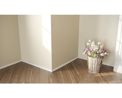 Raumecke mit Holzfußboden, weißen Sockelleisten und Blumenarrangement in einem Korb