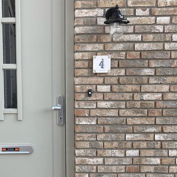 Hauseingang mit grauer Haustür, silbernem Türgriff, Klinkerwand, Außenleuchte, Hausnummer und Klingel.