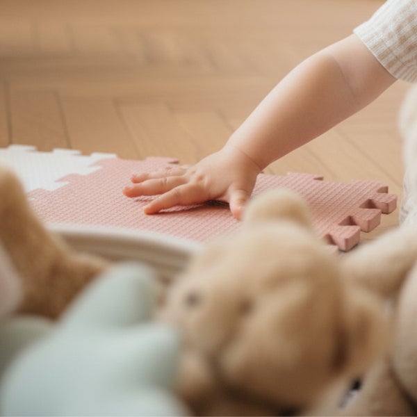 Kind spielt auf einer Puzzlematte auf einem Parkettboden mit Stofftieren