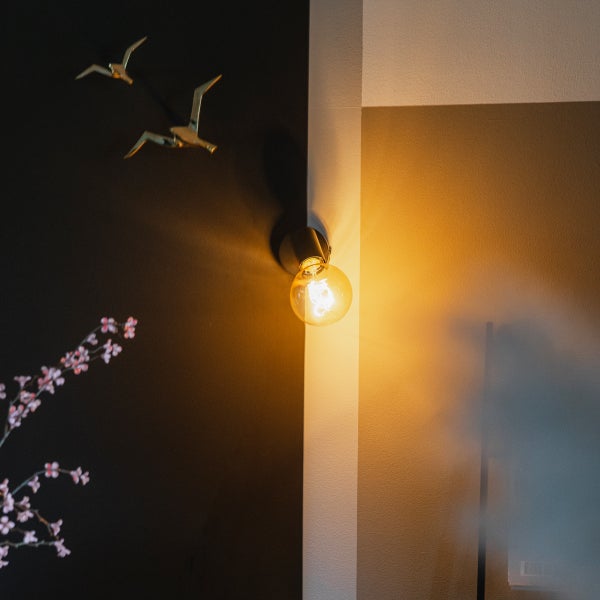 Wandleuchte mit runder Glühbirne an Wand montiert