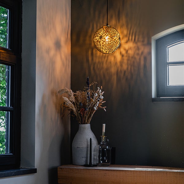 Dekoratives Interieur mit Hängelampe, Blumenvase und Kerzenständern