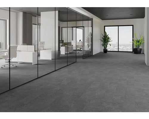 Helles, geräumiges Büro mit Bodenbelag in Steinoptik, Glastrennwänden, Schreibtischen und Zimmerpflanzen.