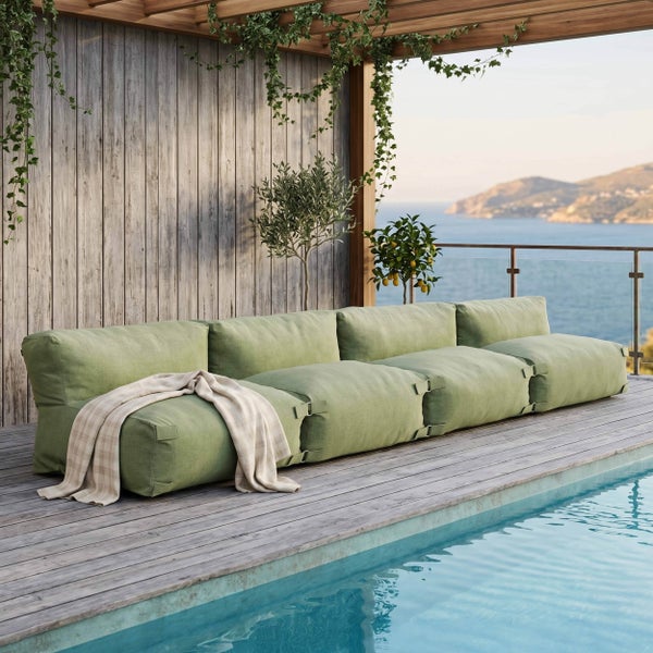 Modulares grünes Lounge-Sofa auf einer Holzterrasse am Pool mit Meerblick und Pflanzen.