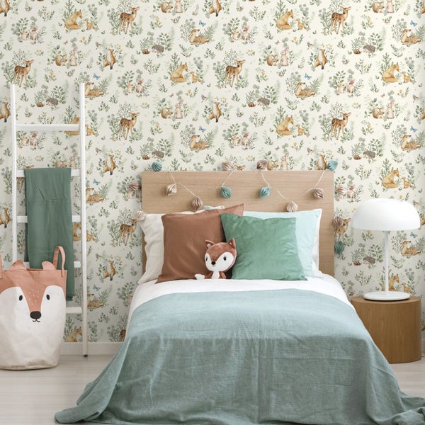 Kindertapete mit Waldtiermotiv wie Rehe und Füchse in einem hellen Kinderzimmer mit Holzbett und grüner Bettwäsche.