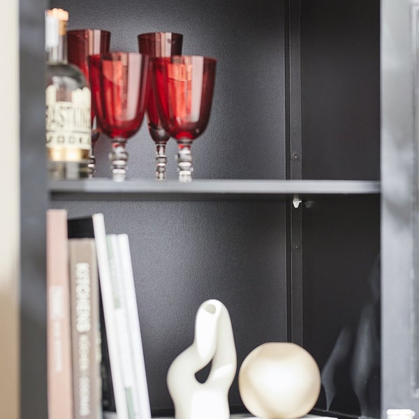 Innenansicht eines Schranks mit Gläsern, Flasche, Büchern und Dekoration