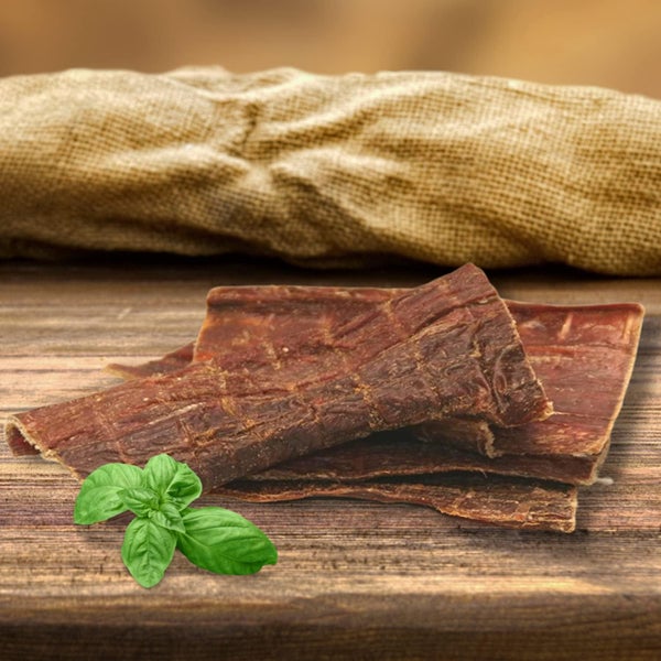 Nahaufnahme von getrocknetem Fleisch mit Basilikum auf einem Holztisch