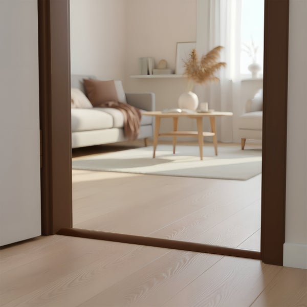 Dunkelbraune Türschwelle aus Metall als Abschluss für einen hellen Holzboden, eingebaut in einen Türrahmen in einem modern eingerichteten Wohnraum.